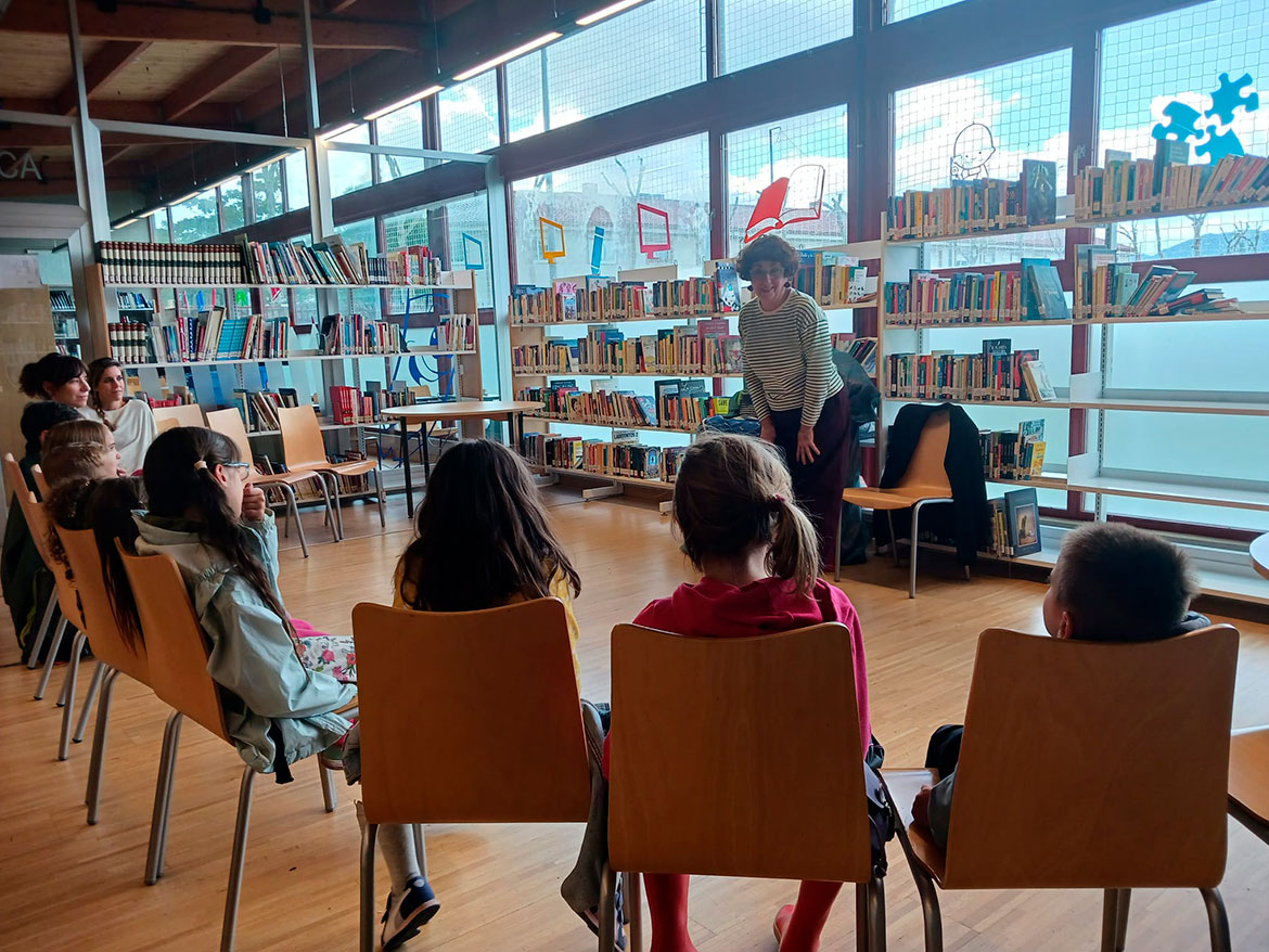 Mujer contando un cuento a unos niños en una biblioteca