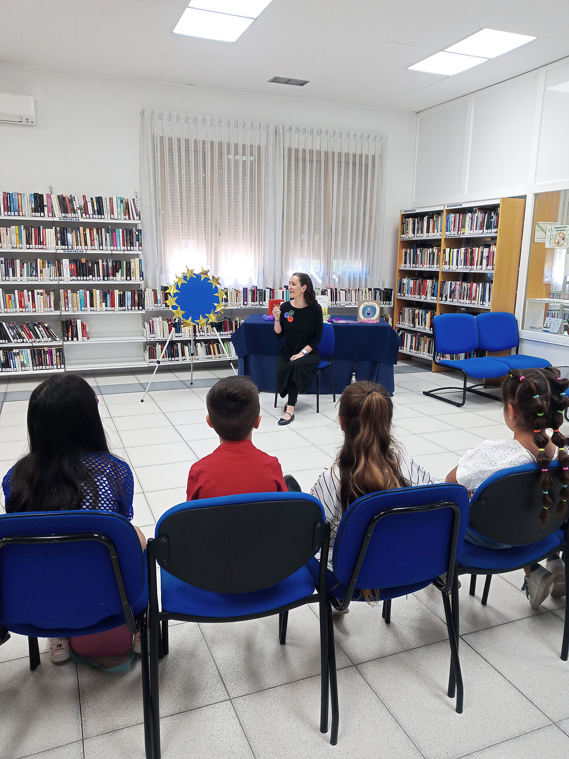 Mujer contando un cuento a un grupo de niños sentados