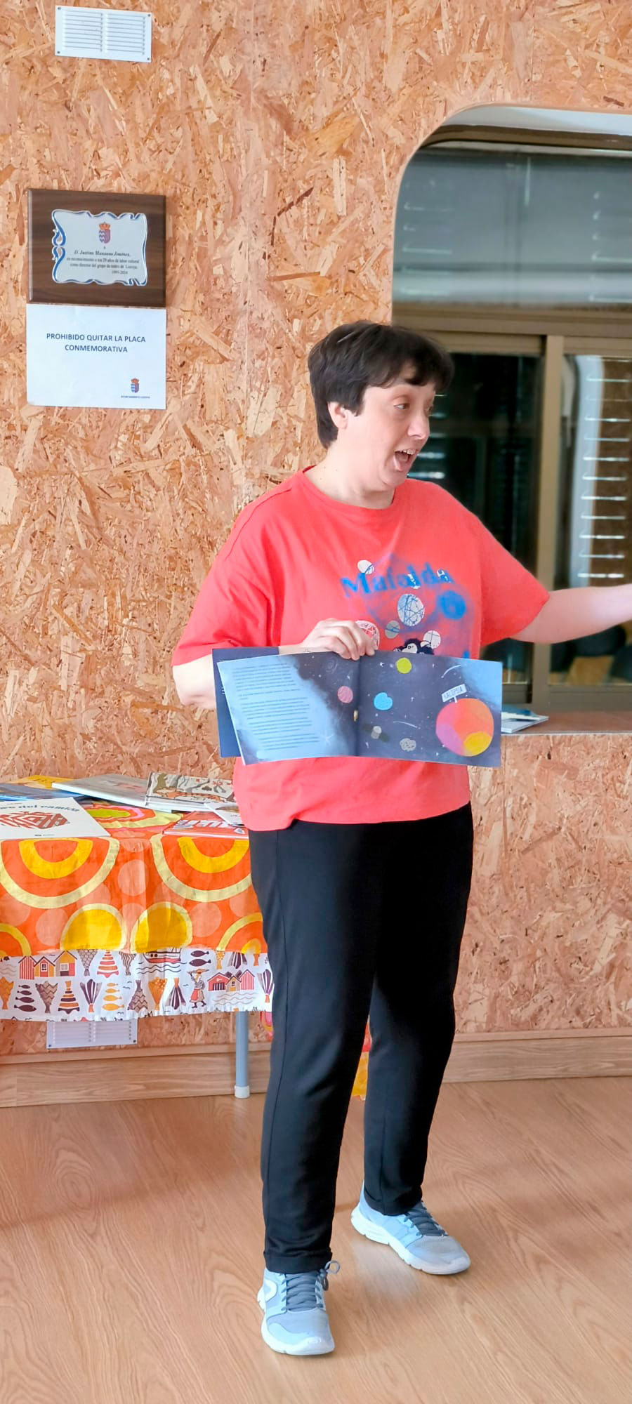 Mujer explicando un cuento que muestra abierto en una mano