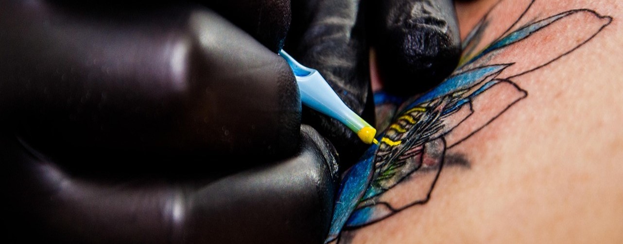 Tatuador Manos de tatuador con guantes negros aplicando un tatuaje