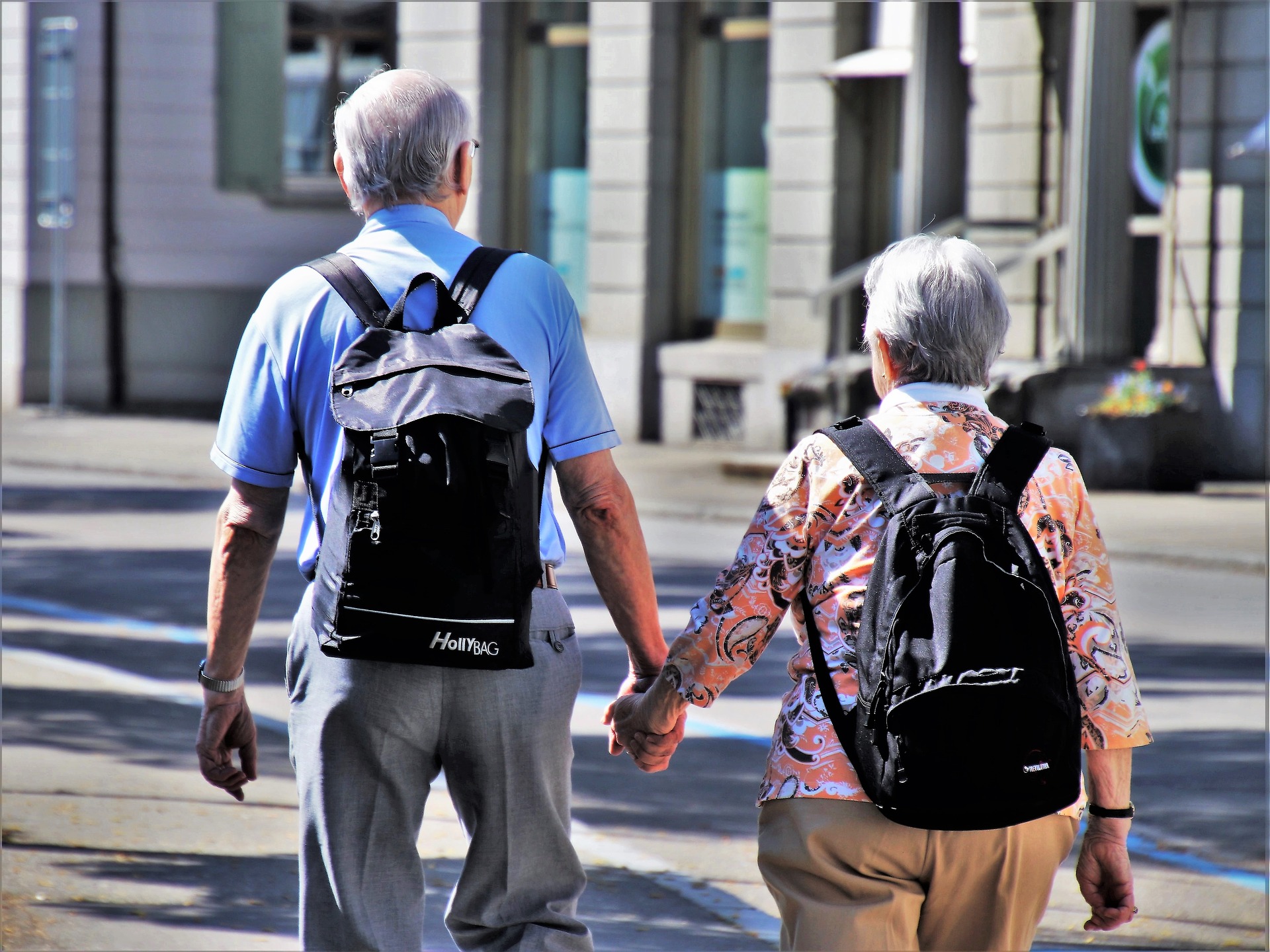 Señores mayores con mochilas caminando de la mano