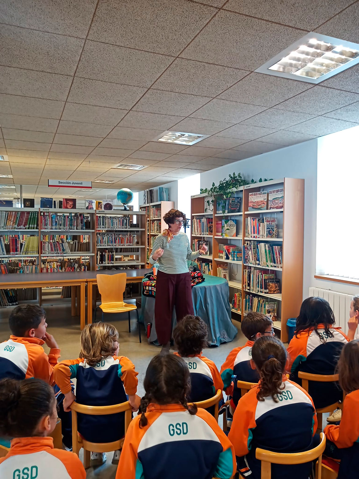 Mujer contando un cuento a un grupo de niños en una biblioteca