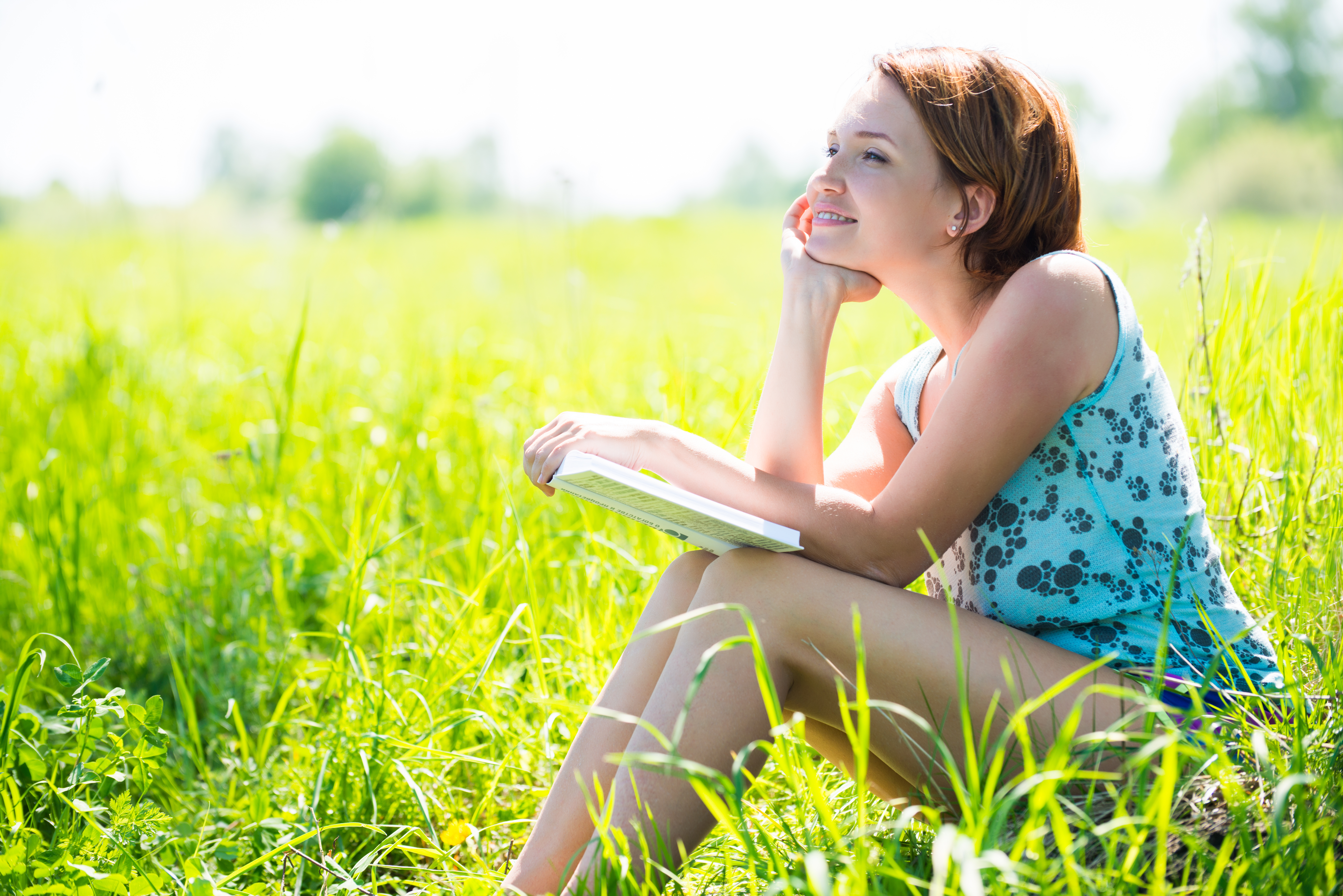 chica feliz leyendo sentada en la hierba
