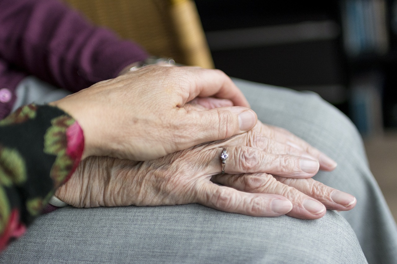 Mano de mujer encima de una mano de una anciana 