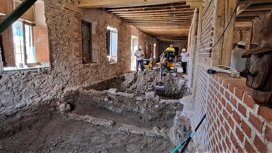 Un operario maneja una excavadora en la galería sur junto a dos operarios, de pie