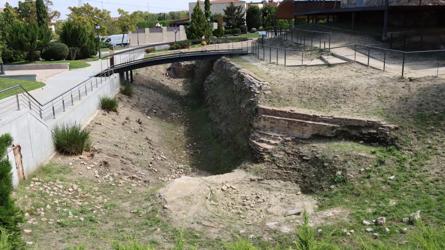 foso de un castillo con muralla de piedra y vegetación