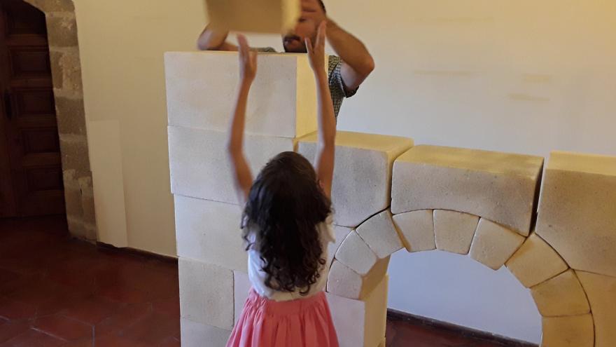 Hombre y niña jugando con bloques creando un arco y una torre arquitectónica