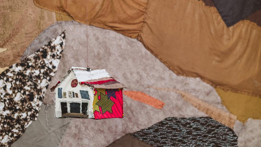 Casita realizada en tela colgando delante de otra tela