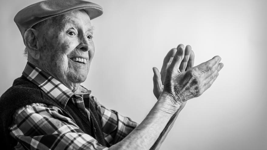 Anciano tocado con una gorra y dando palmas