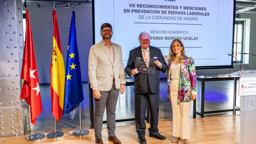 Autoridades y premiado en escenario con premio
