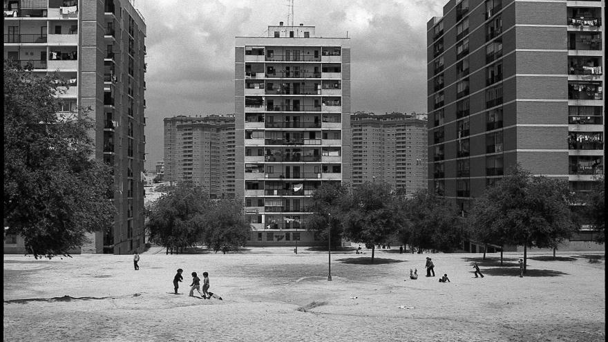 Fotografía de Javier Campano, parque con niños jugando, al fondo diferentes bloques de edificios altos en el barrio de El Pilar en Madrid