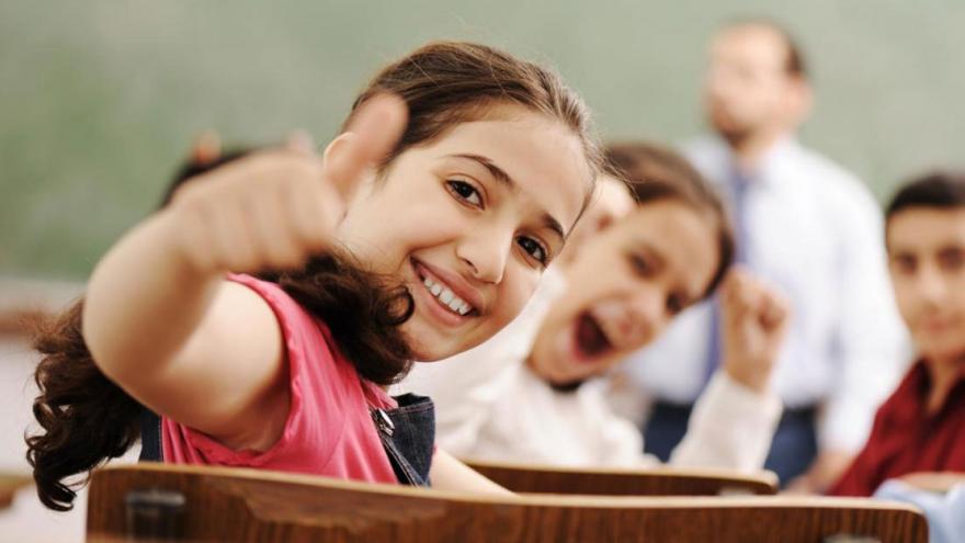 Escolares en sus pupitres sonriendo