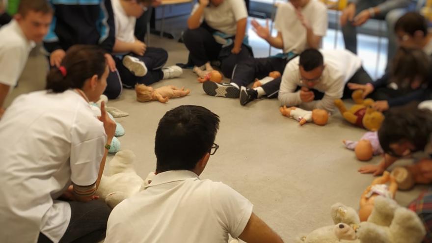 Estudiantes en corro atendiendo explicación de profesor