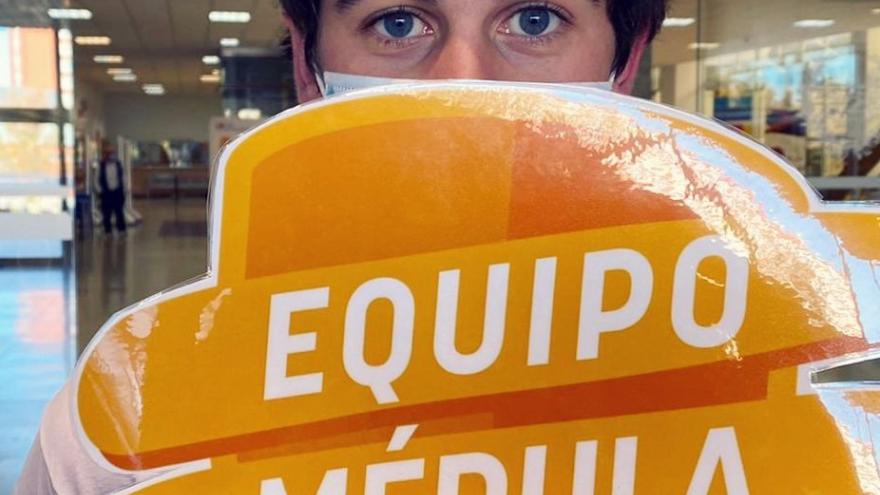 Joven con un cartel delante de la cara con el logo escudo equipo médula