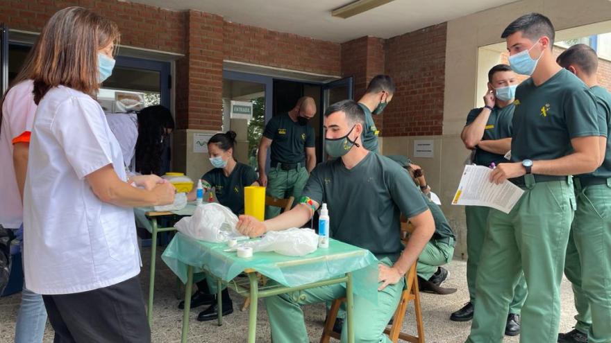 Enfermera y joven guardia extrayéndole tubo sangre