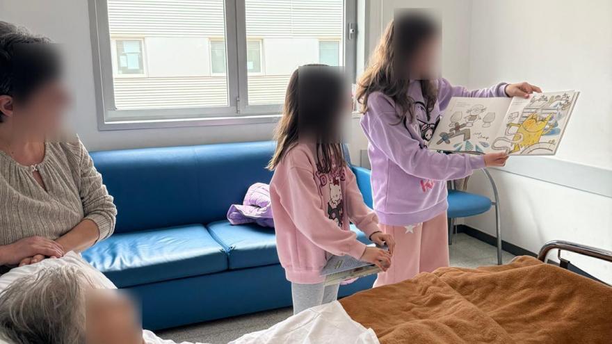 Niñas leen a paciente en cama