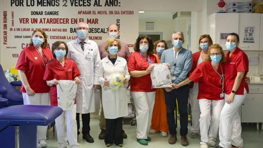 Profesionales sanitarios con un vinilo en la pared de fondo con frases alusivas a donar sangre por lo menos dos veces año