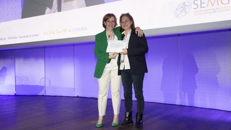 La ganadora del premio a la mejor comunicación oral de investigación en primaria recibe su galardón en el escenario