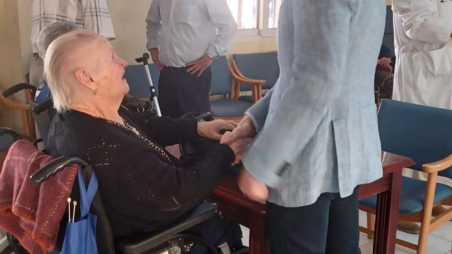 Mujer mayor en silla de ruedas hablando con hombre joven de pie