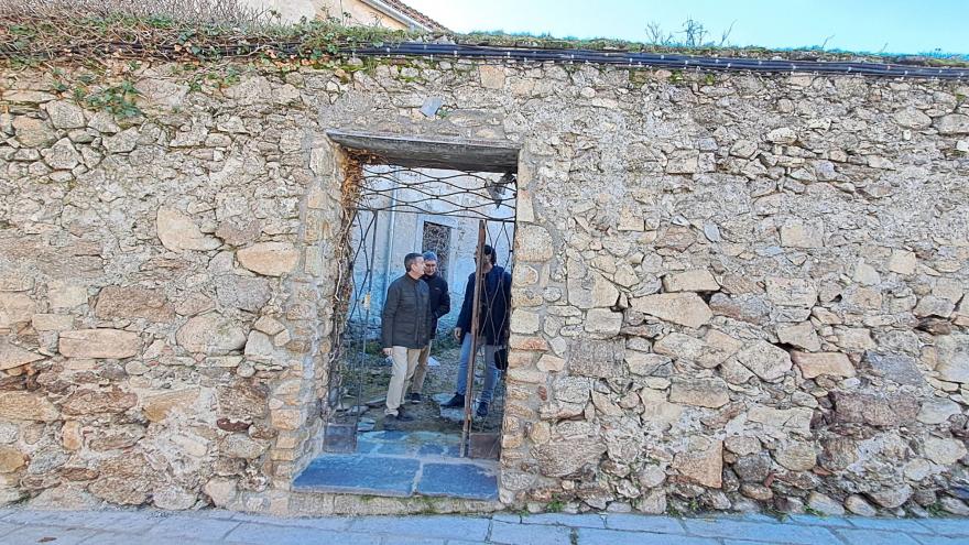 Estado inicial de la puerta – reja en el muro del patio norte. Elementos espurios y degradación constructiva imagen de dos hombres atravesando la puerta de una fachada de piedra