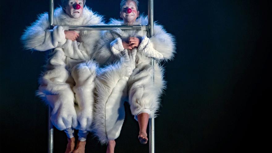 Dos payasos vestidos de blanco sentados en una escalera 