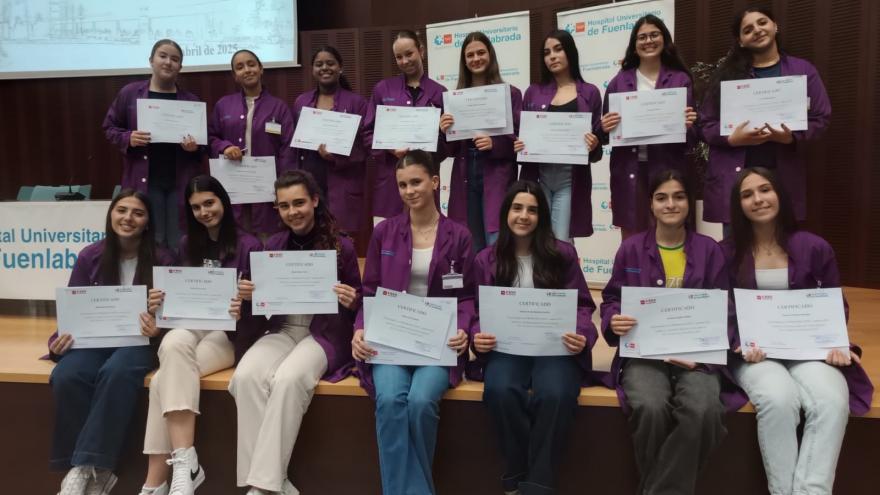 Estudiantes en un escenario con sus diplomas