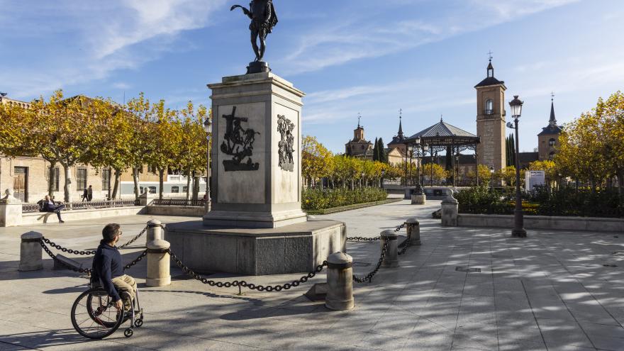 Plaza de Alcalá de Henares con una persona en silla de ruedas paseando 