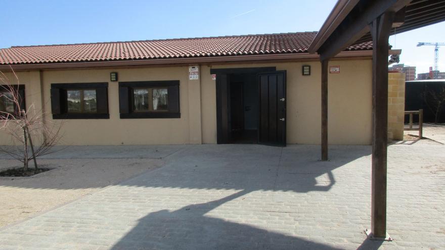 Fachada principal con puerta de entrada y ventanas, y pérgola en un lateral