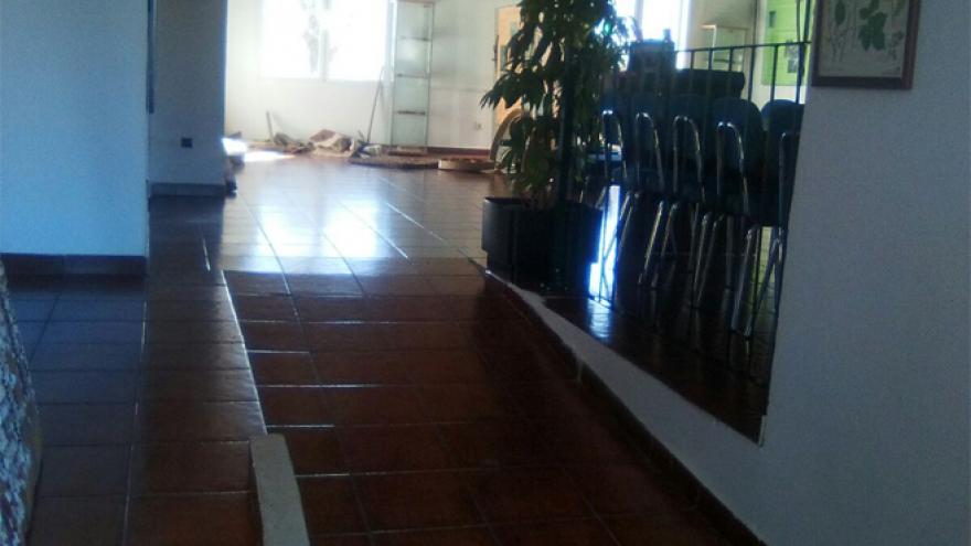 Pasillo en rampa y al fondo habitación con sillas y techo de madera