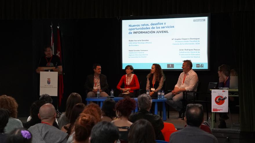 4 personas en escenario con micrófonos para hablar al público