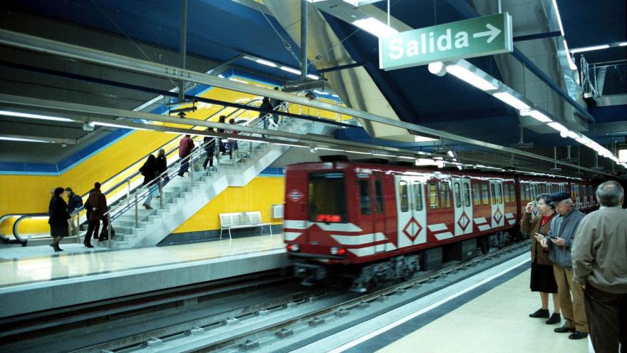 Tren saliendo de la estación Villa de Vallecas, personas utilizando las escaleras