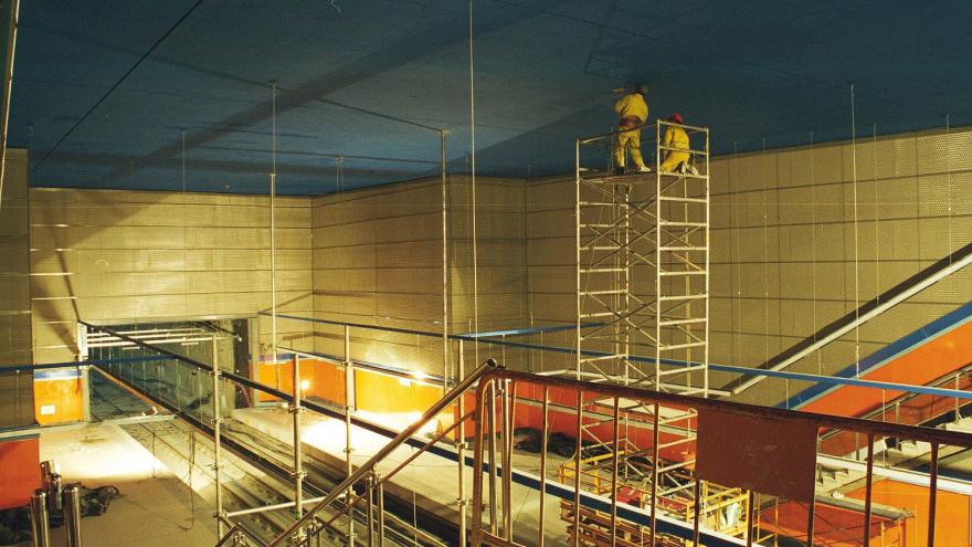 Obreros subidos a un andamio pintando el techo de azul de la estación Congosto