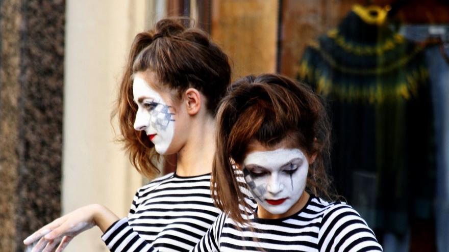 Dos jóvenes con la cara pintada de blanco actuando de mimos