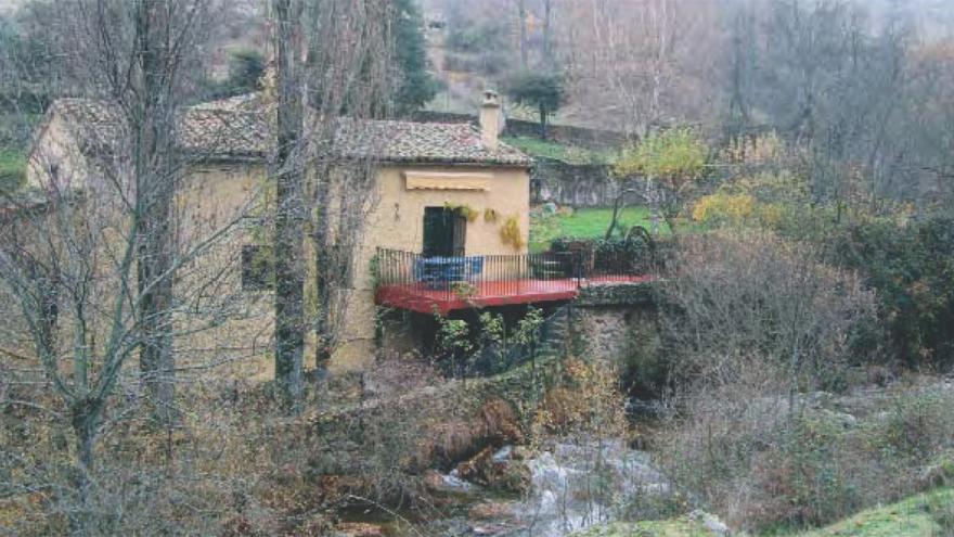 Molino de agua en el borde de un río rodeado de árboles