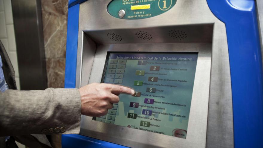 Mano seleccionando un billete en una máquina expendedora de Metro