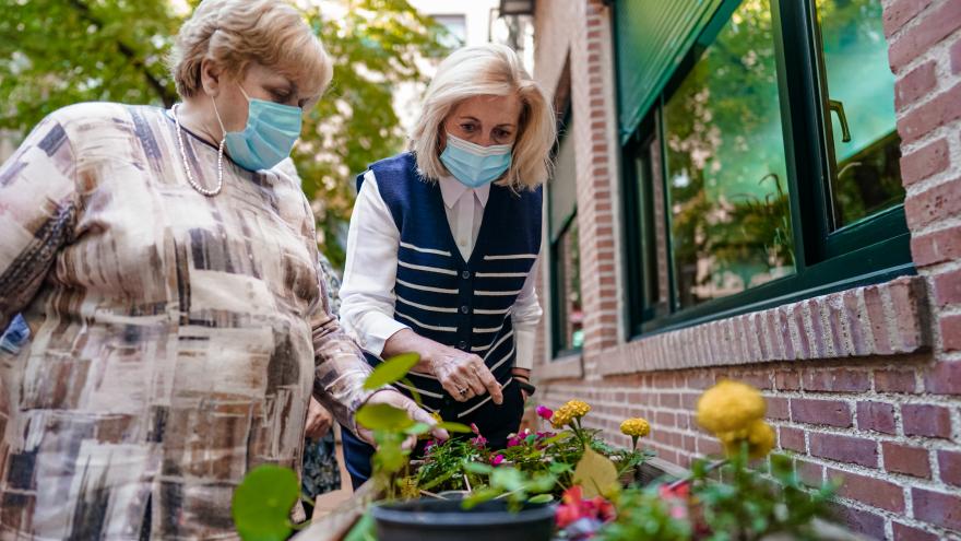 La consejera junto a una persona mayor que está regando unas flores