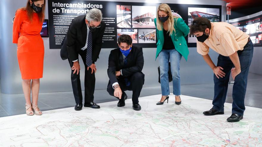 El consejero junto con otras personas agachado mirando un mapa gigante en el suelo
