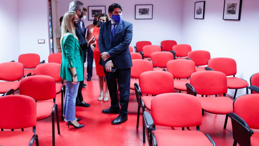 El consejero junto con otros acompañantes en una sala con muchas sillas rojas en filas