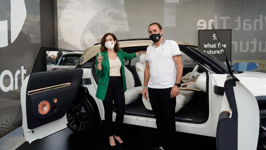 La presidenta de pie en la puerta de un coche hablando con el responsable de la marca