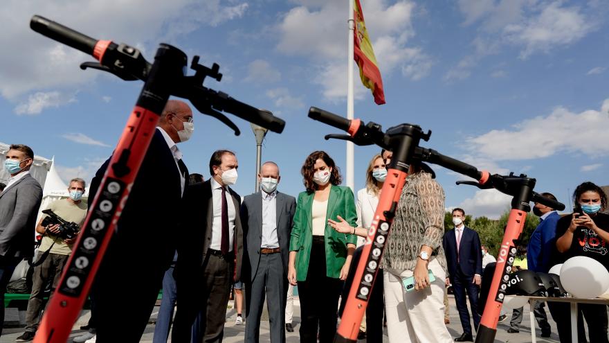 La presidenta acompañada por otros asistentes mirando unos patinetes eléctricos