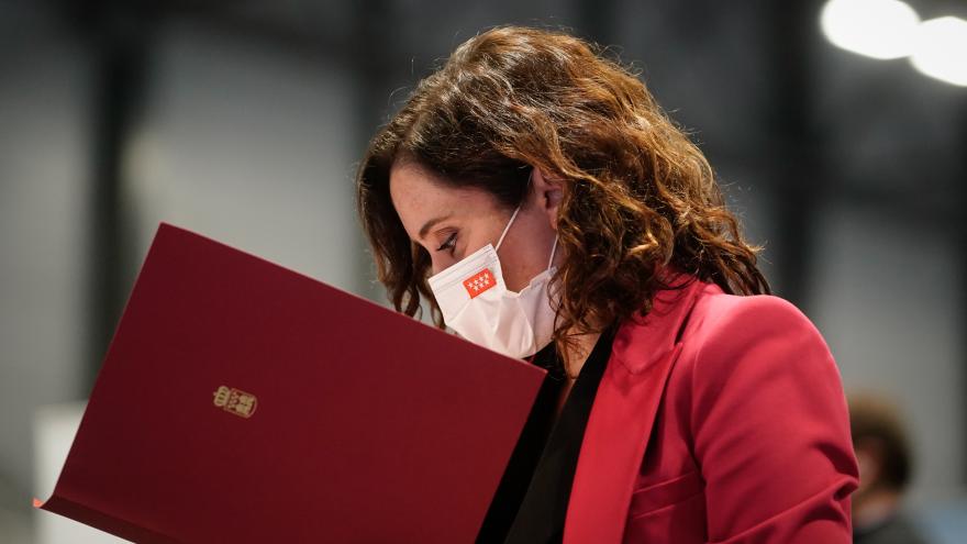 La presidenta mirando una carpeta de la Comunidad de Madrid