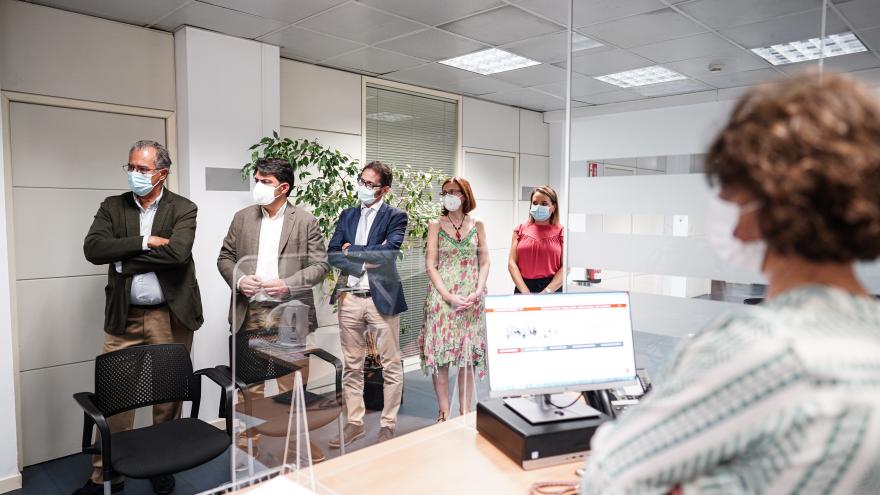 El consejero junto con otras personas de pie escuchando las explicaciones de alguien fuera de plano