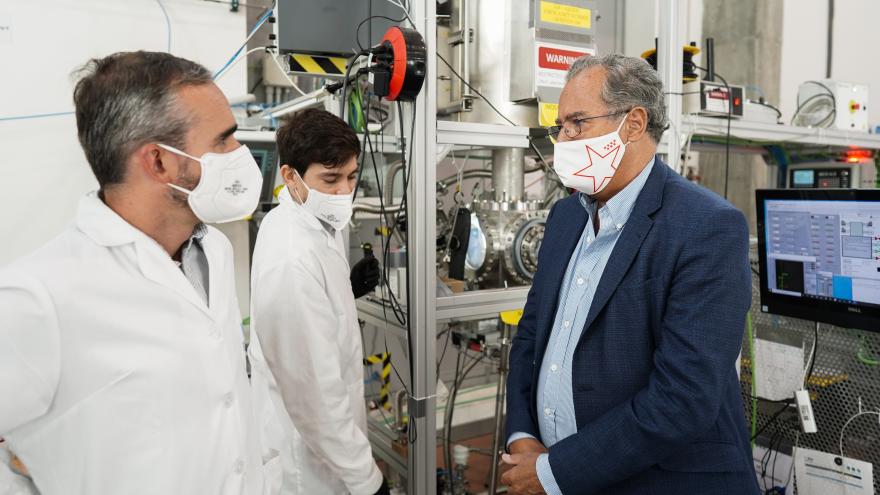 El consejero hablando con dos de los técnicos delante de maquinaría electrónica