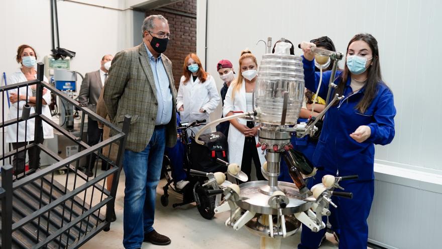 El consejero mirando una de las máquinas productoras de vino mientras atiende a la explicación de los alumnos sobre la misma