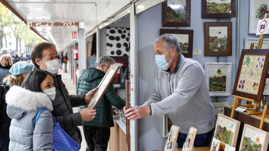 Personas mirando los cuadros de uno de los puests