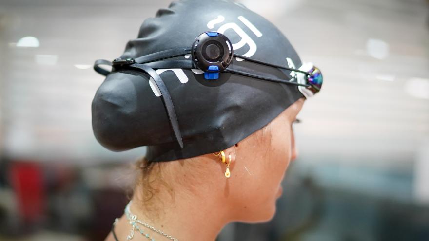 Primer plano de una nadadora con gorro de piscina y un aparato tecnológico en el mismo