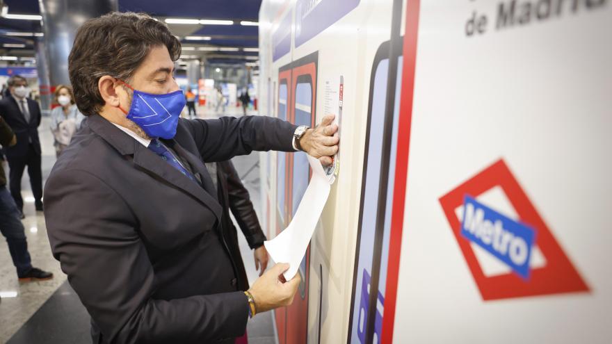 El consejero de transportes pegando uno de los carteles