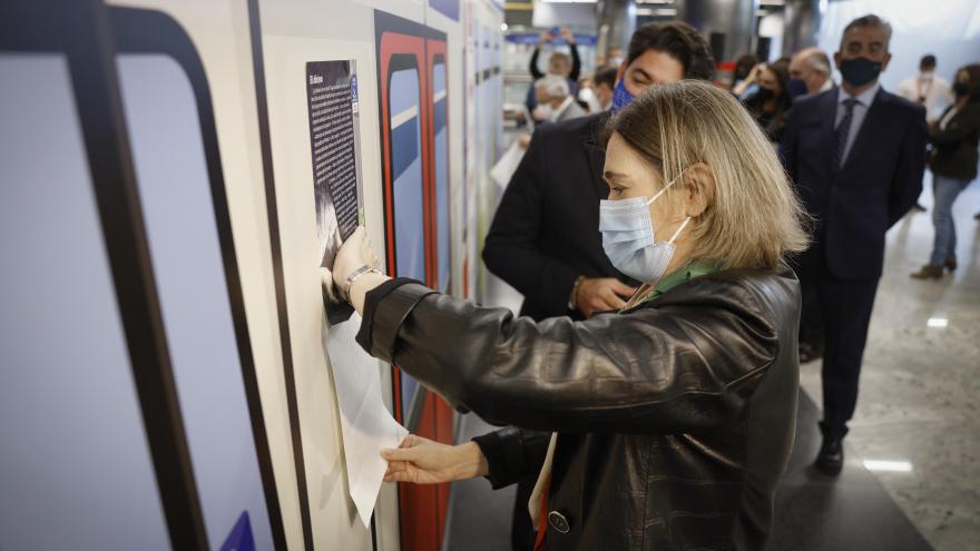La consejera de cultura pegando uno de los carteles en un vagón de metro