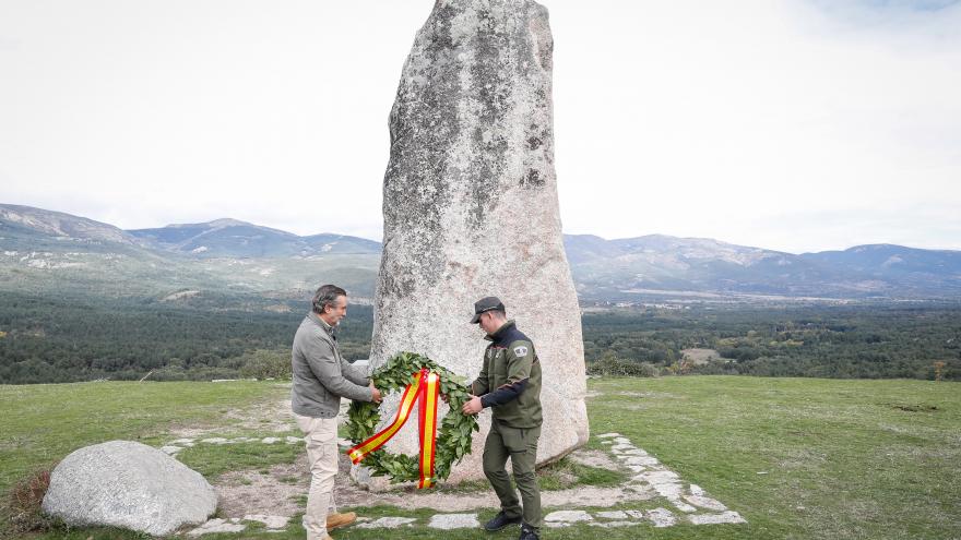 El consejero junto a uno de los agentes dejando una corona de laurel en homenaje
