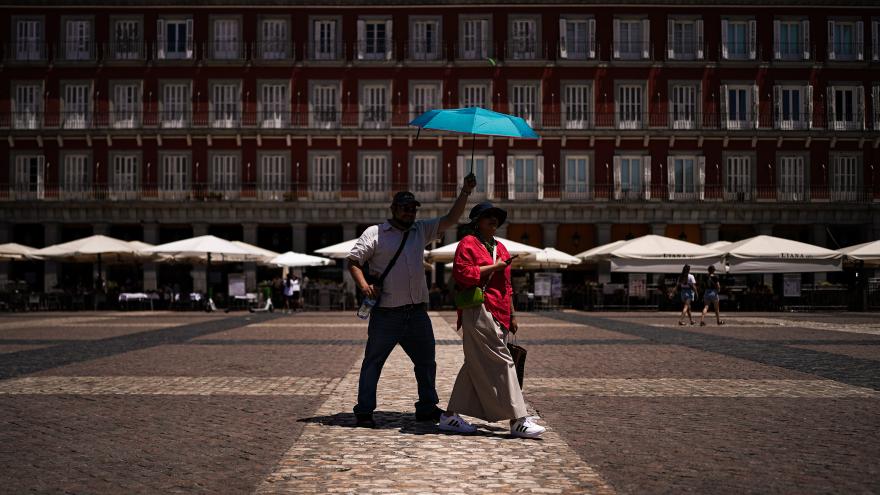 Dos personas paseando con paraguas por la plaza mayor